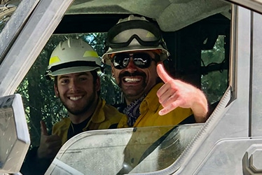 two smiling men inside utv