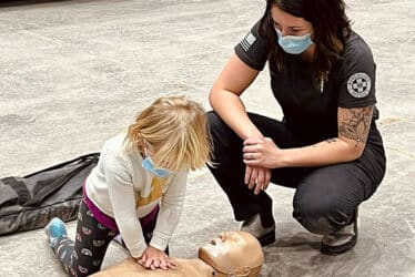 Woman overseeing child learning CPR