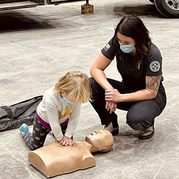 Woman overseeing child learning CPR